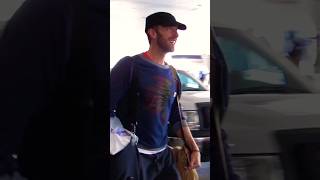 Smiling Chris Martin Carries Own Bags at Airport in Fave Native Indian Chief Tee