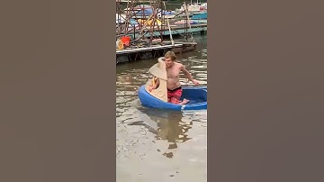 Guy puts a motor on a tugboat sandbox, and takes it in the lake.