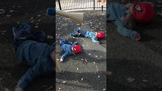 Boy wearing Spider-Man masks roll around on floor at playground then one bumps head on metal horn