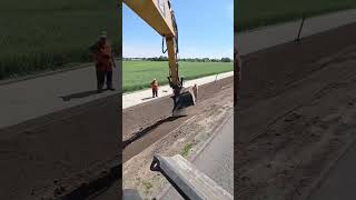 Professional Excavator Operator at Work: Precise Topsoil Spreading in Slope Formation