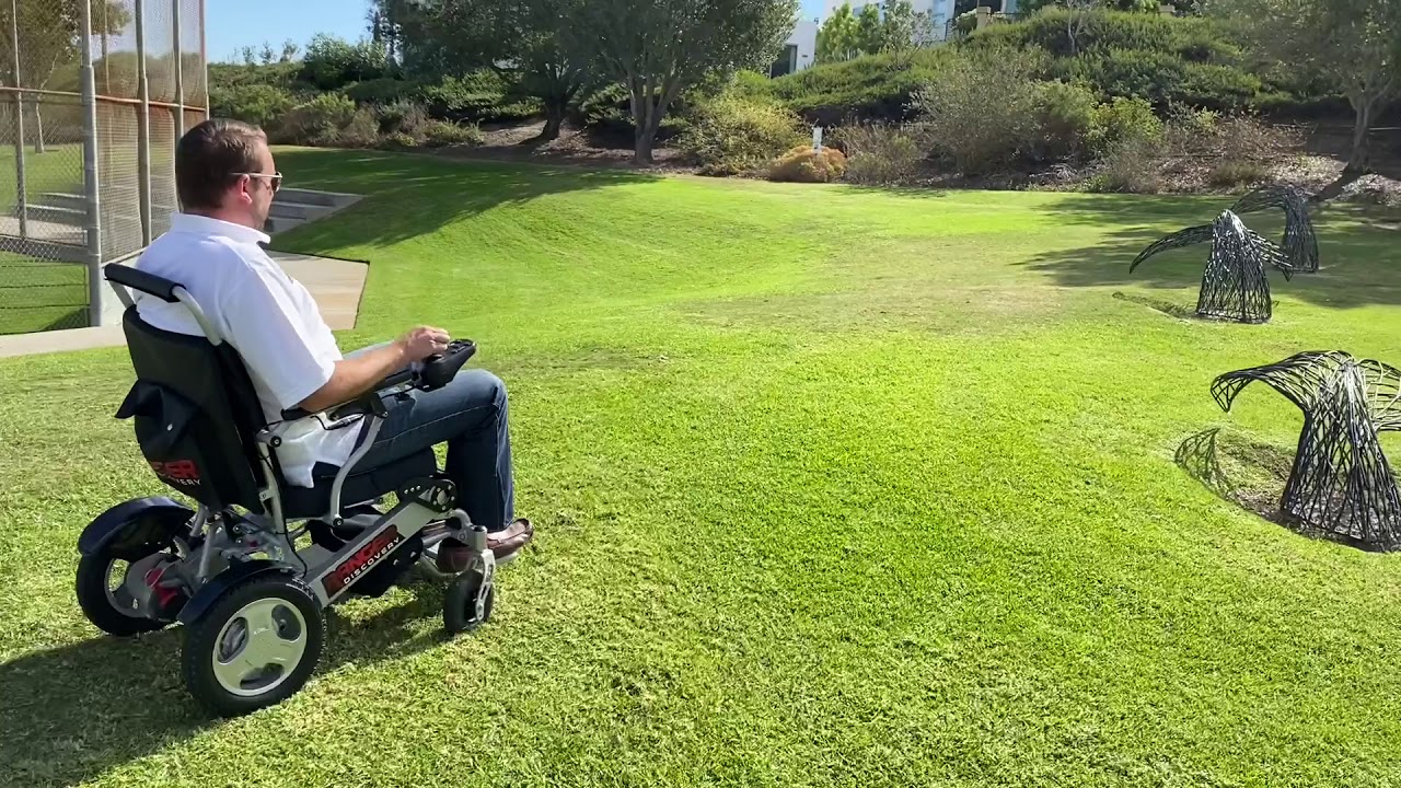 Ranger D09 Foldable Lightweight Power wheelchair cruising smoothly over grass with some obstacles.