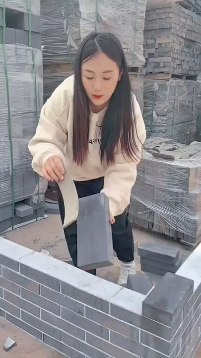 Carefully arranging gray bricks while building a neat corner wall structure