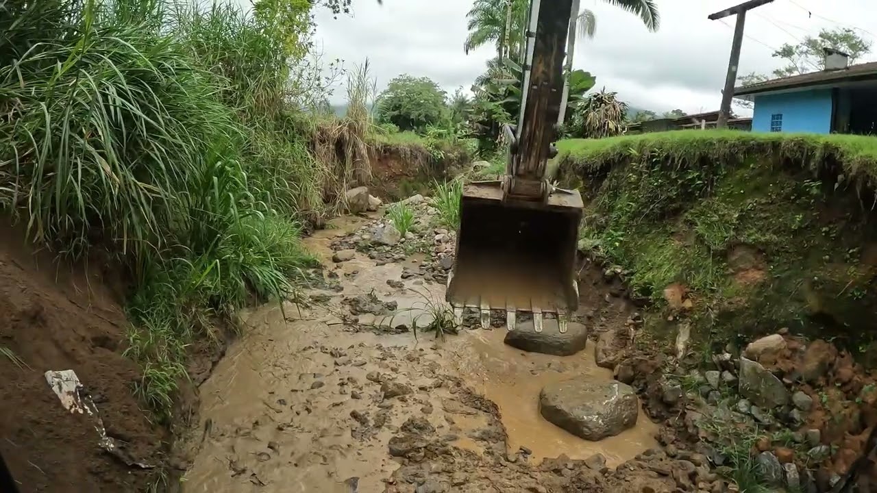 Escavadeira fazendo contenção de pedras em curvas de rio p1