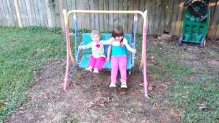 Two girls fall backwards on a bench swing