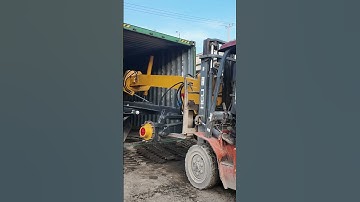 using a folklift to push excavator grader into a 40ft container