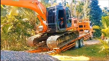 The process of loading and unloading an excavator onto a self-loader truck.