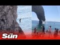 Lads 200ft rock jump as beach crowds cheer unaware theyve been seriously injured by the fall