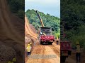 トラックが山道をゆっくり走り、ケーブルを溝に敷設しながら作業員が押し込む：移動式ケーブル布設と溝内整備の連携作業