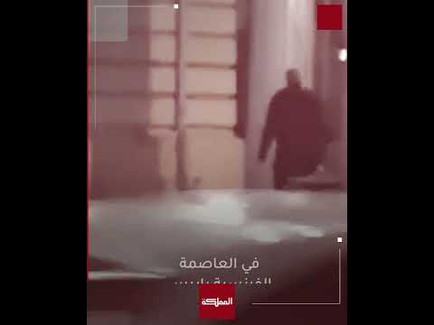 أفراد أمن فرنسيون يرشون الغاز المسيل للدموع على أمتعة مهاجرين تركوها أسفل جسر في باريس