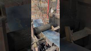 The metal sheet is being rolled using a rolling machine and will be used in industrial work
