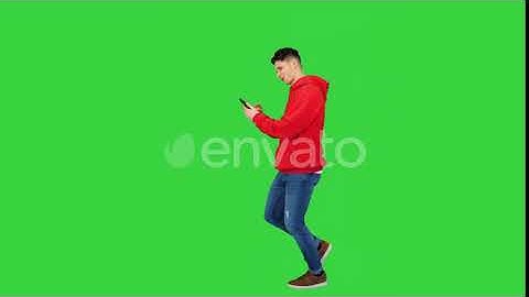 Handsome Cool Casual Man Listening To Music in Smartphone and Dancing While Walking on a Green S...