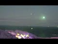 A large Orb floating above the Irish Sea shines green light that is reflected in the water. May 2022