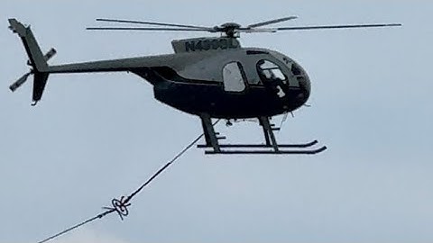 Helicopter pulling electrical cable through towers
