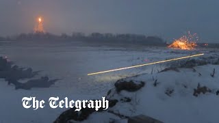 Mobilised Russian troops fire rifles at night in snowy conditions