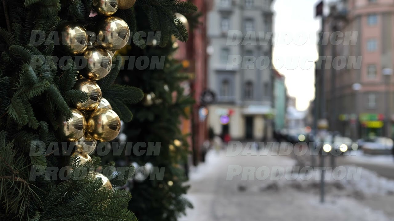 Golden christmas balls decorating a christmas tree on a blurred city street