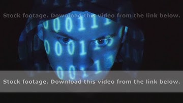 Hooded hacker working on a computer, binary code projecting on his face.