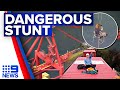 Climate change activist suspended from crane as demonstrations continue | 9 News Australia