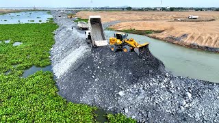 Constructing WaterBased Highway WheelLoader effortlessly rolls big stone to water , truck spreading