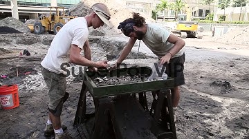 Long shot of two archeologists sifting mud in search for ...