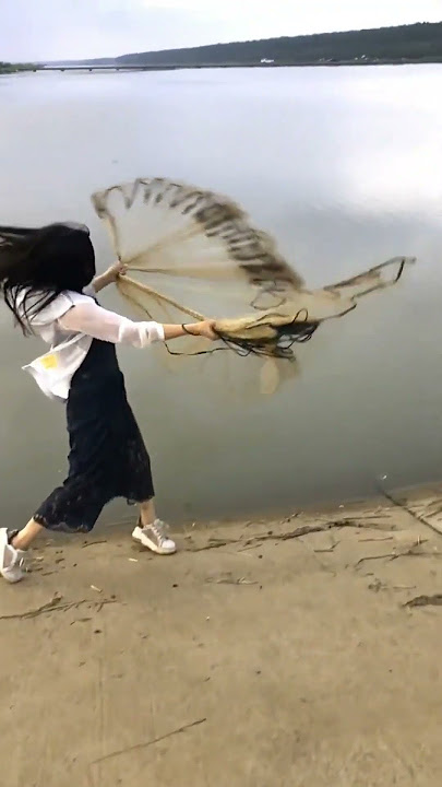 A beautiful girl casting nets by the lake