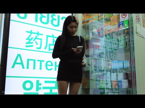 Walking on the streets of Pattaya, a beautiful girl plays with her phone alone. Myth Night.