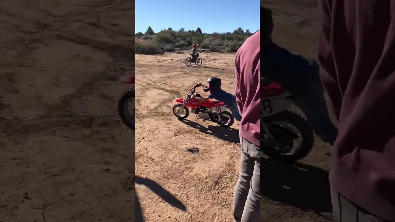Boy in full face helmet crashes dirt bike into front tire of truck