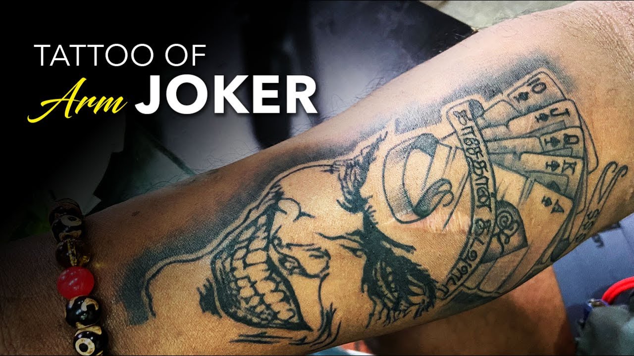 Sketch work The Joker tattoo on the upper arm.