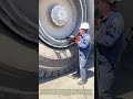 Torque Securing: Crew Tightens Wheel Fasteners On Oversized Mining Hauler Tire