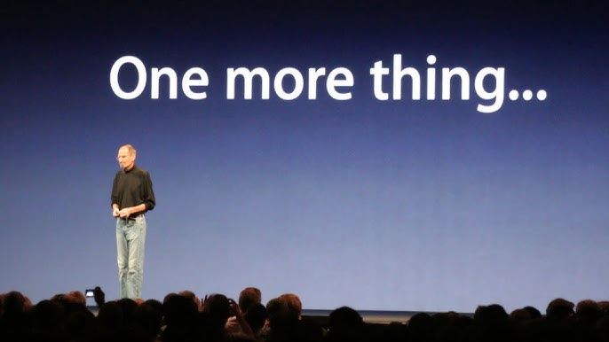 steve jobs on stage with one more thing slide showing dramatic lighting and audience reaction