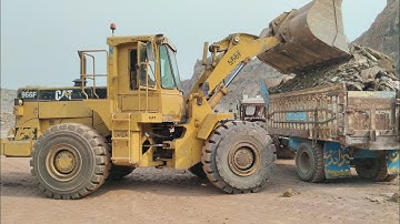 Caterpillar 966F Model Wheel Loader is Loading Rocks into Big Trolleys