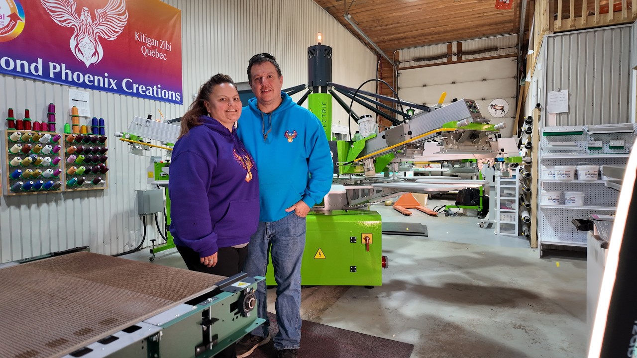 Founder Pamela Menaes of Diamond Phoenix Creations stands proudly infront of her ROQ E Automatic Screen Printing Press
