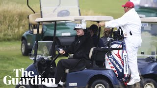 President Trump waves to protesters as he plays golf in Scotland