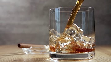 Jet of Whiskey in a Glass With Ice. Slow Motion