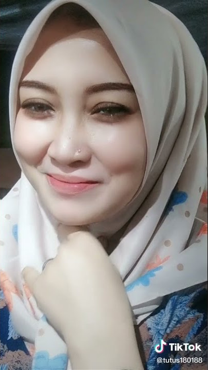 cewek hijab senyum senyum depan kamera sambil mainin itunya