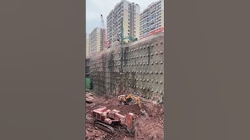 Anchored retaining wall shoring system reinforced with a telescopic grab bucket excavator.