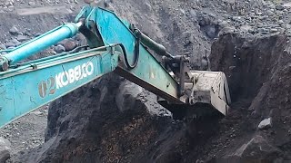 excavator working to tear down sand cliffs and load them into truck beds - sand mining