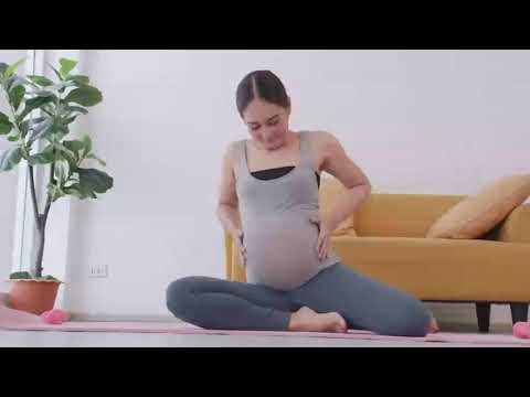 Beautiful young Asian pregnant woman in sportswear is doing yoga at home