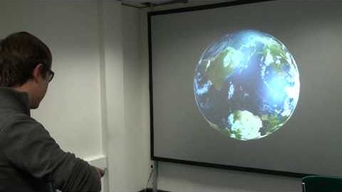 Matthew using a Wii remote to manipulate a 3-D map of the Earth.