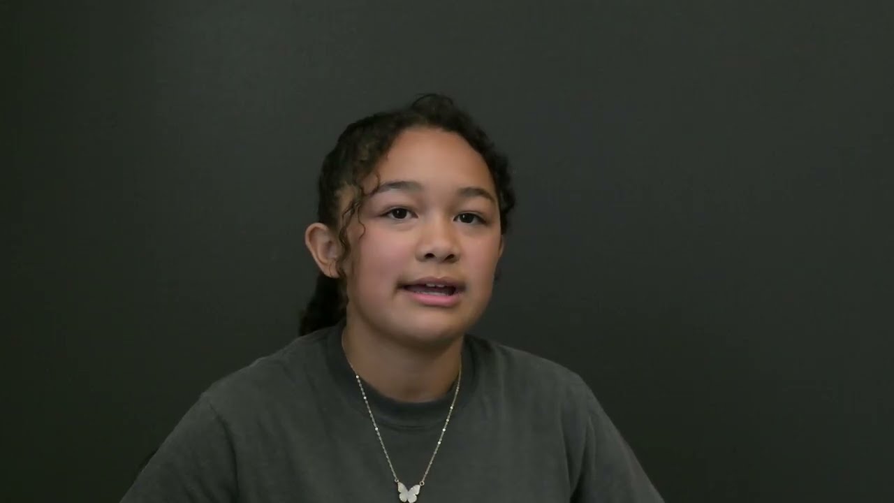 Video preview image of A student in a gray shirt smiles in front of a gray background.; click to visit the ParentSquare post with the video