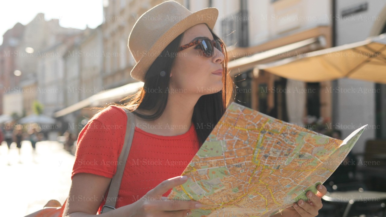 Young woman tourist walking the street with paper map and trying to find right street, place. Woman