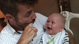 Baby laughing hysterical while dad pops his mouth