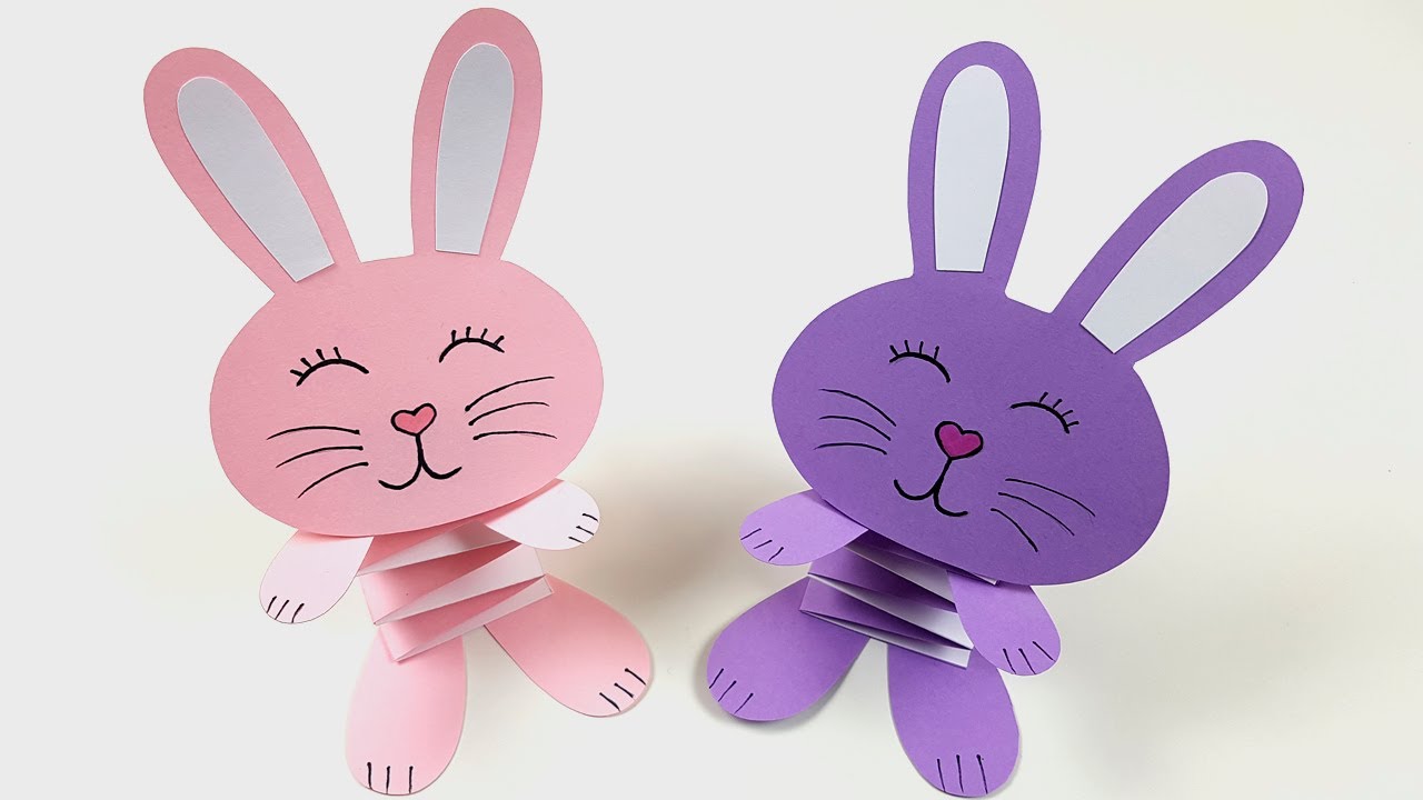 Пасхальные кролики ручной работы из цветной бумаги, легкие поделки для детей на сером фоне.
