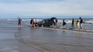 Car stuck on beach as tide come in.