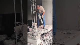 breaking a concrete floor using a powerful electric jackhammer tool at a construction site outdoors