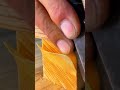 Using a sharp hand chisel tool to shave and smooth the corner edges of a square timber block