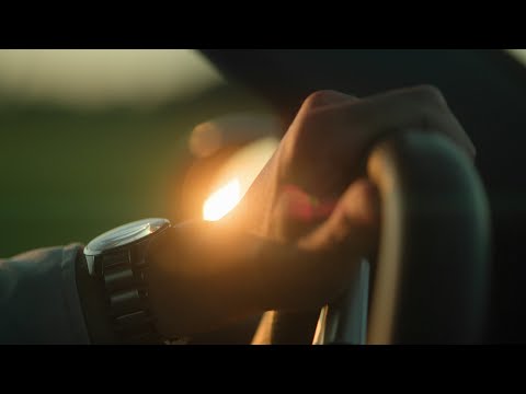 Hands turning steering wheel in sunset