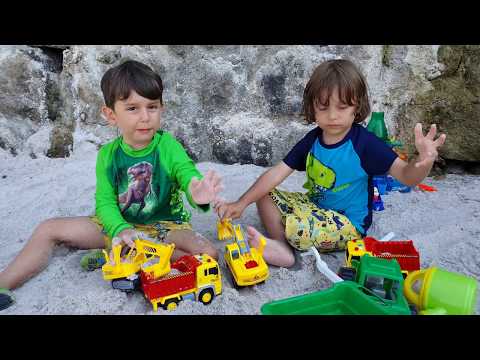 Fatih Selim ve Yusuf plajda kum kamyonu ve kepçe oyuncaklarını açıp oynuyorlar