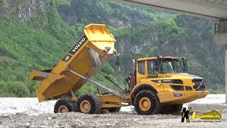 Volvo L90F Wheelloader Pushing Gravel Transported by Cat and Volvo Dumpers