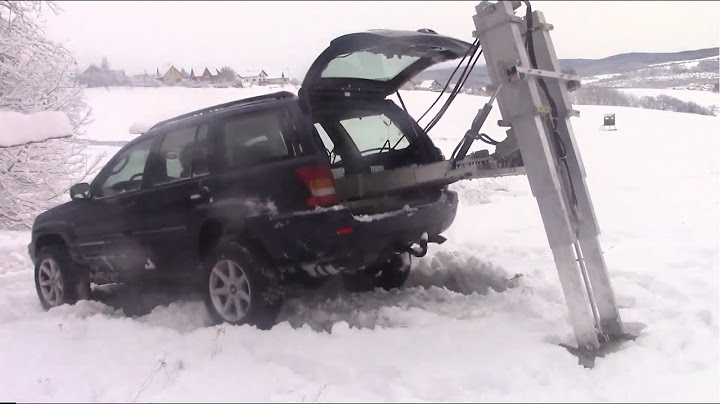 Jeep Geländewagen steckt fest im Schnee aber kommt wieder raus mit Bergehilfe im Kofferraum Traution