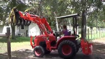 Girl operates a kubota tractor with a root grapple